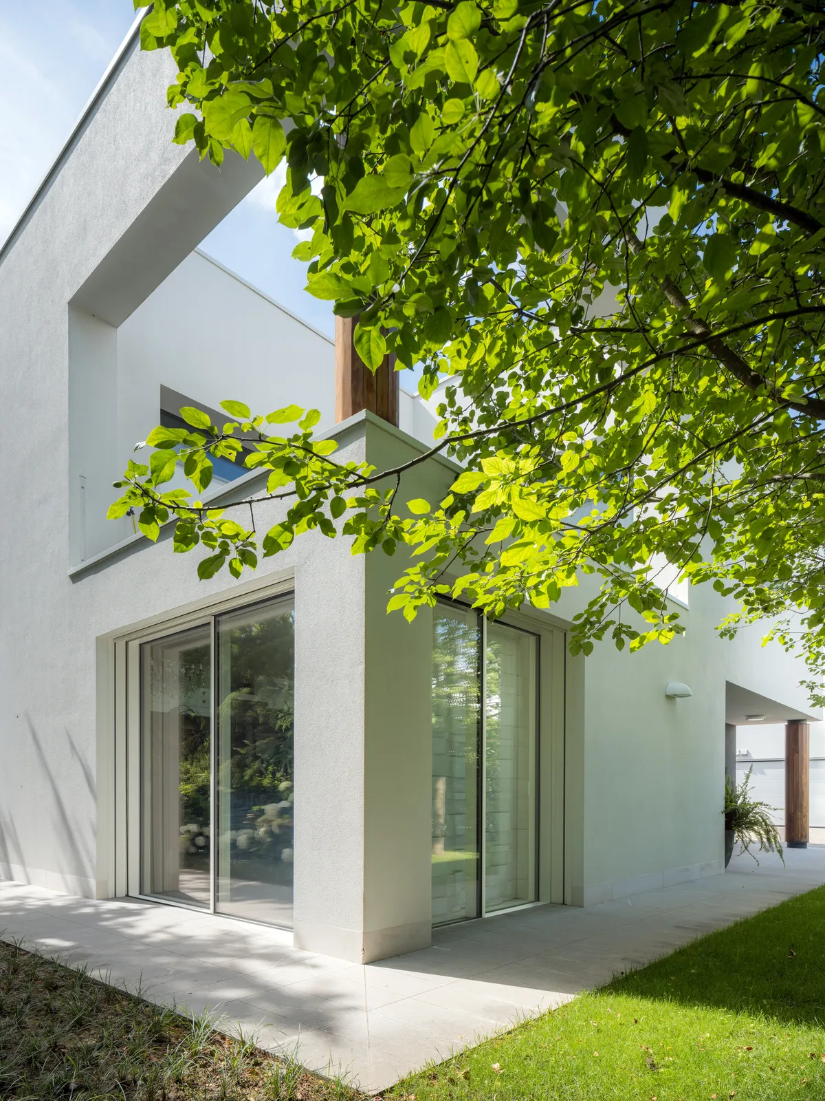 Volumi bianchi della villa con ampie vetrate, immersa nel verde