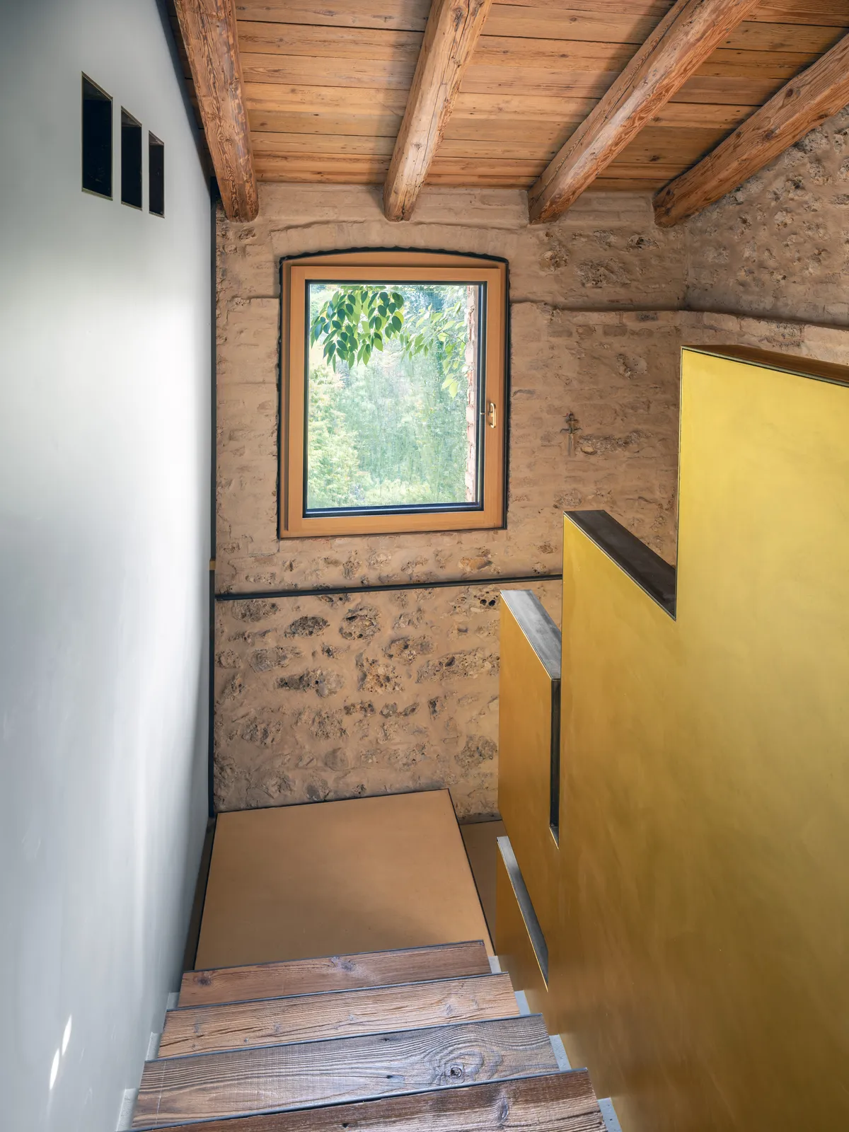 Scala con parete dorata e finestra in larice spazzolato