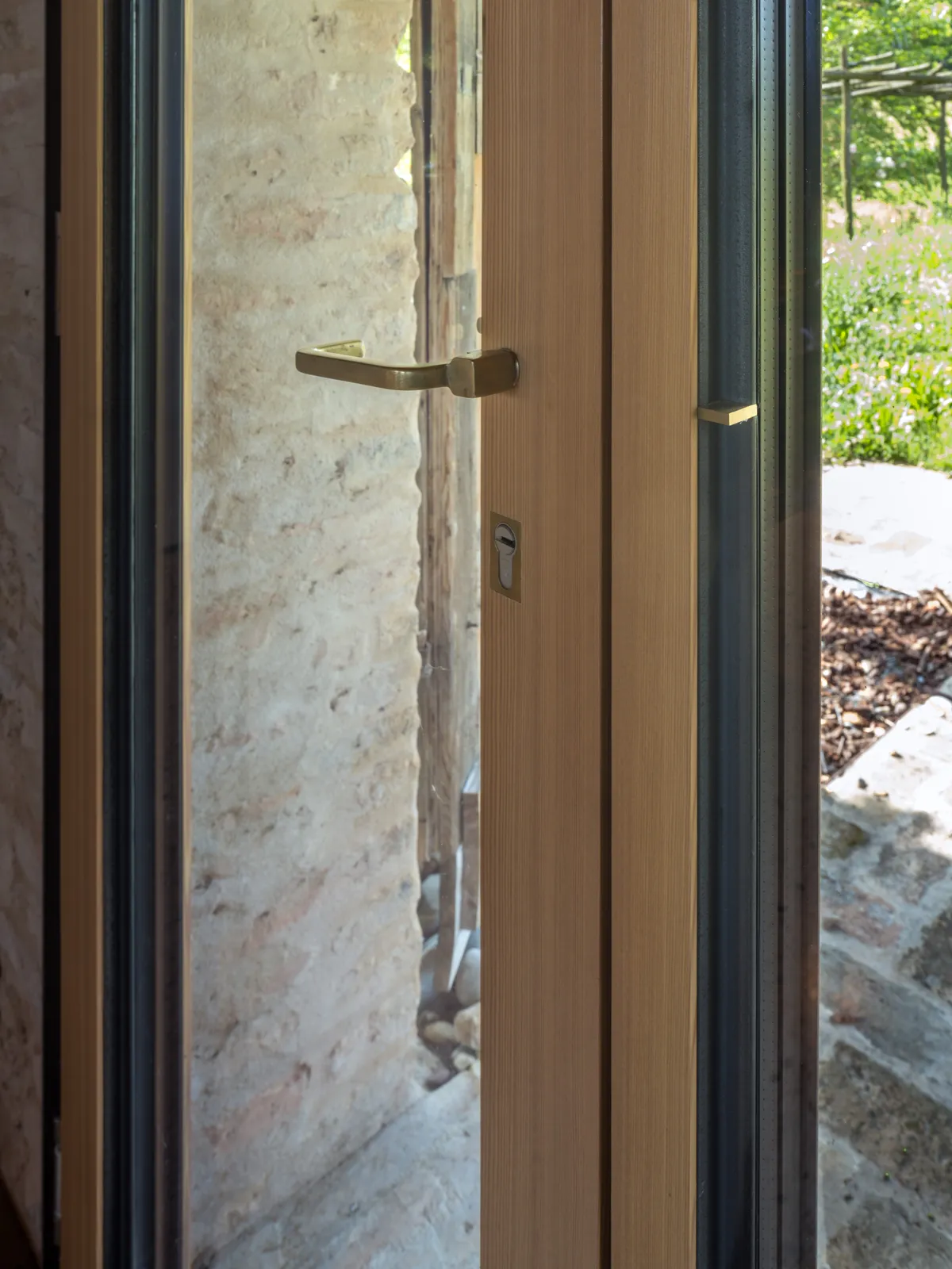 Porta finestra in larice con maniglia in ottone, vista sul giardino