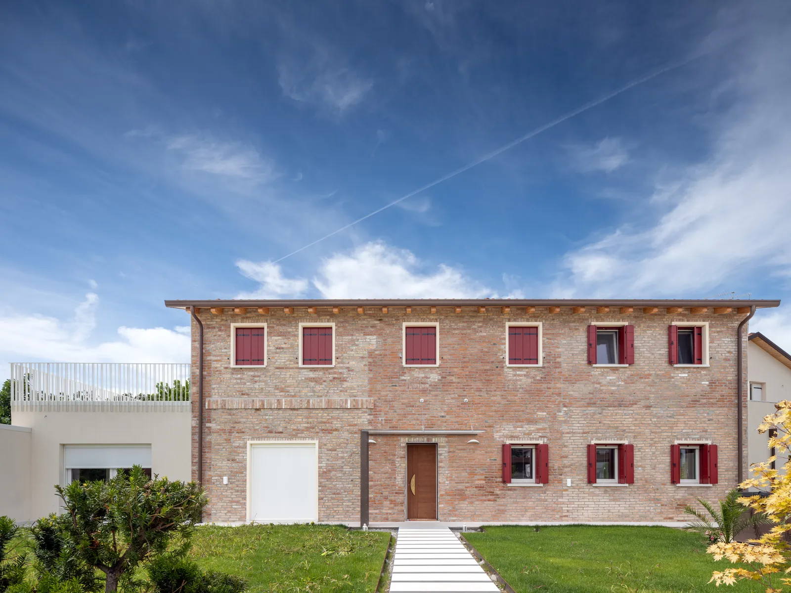 Residenza in mattoni a vista con balconi in legno rossi