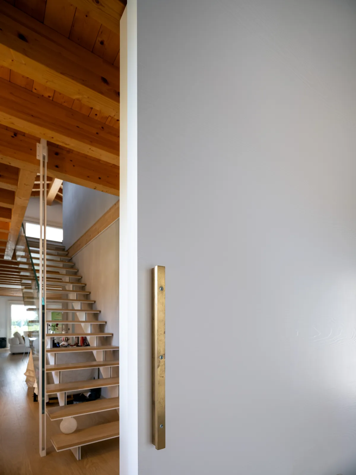 Porta scorrevole interna con maniglione verticale in ottone e scala in legno