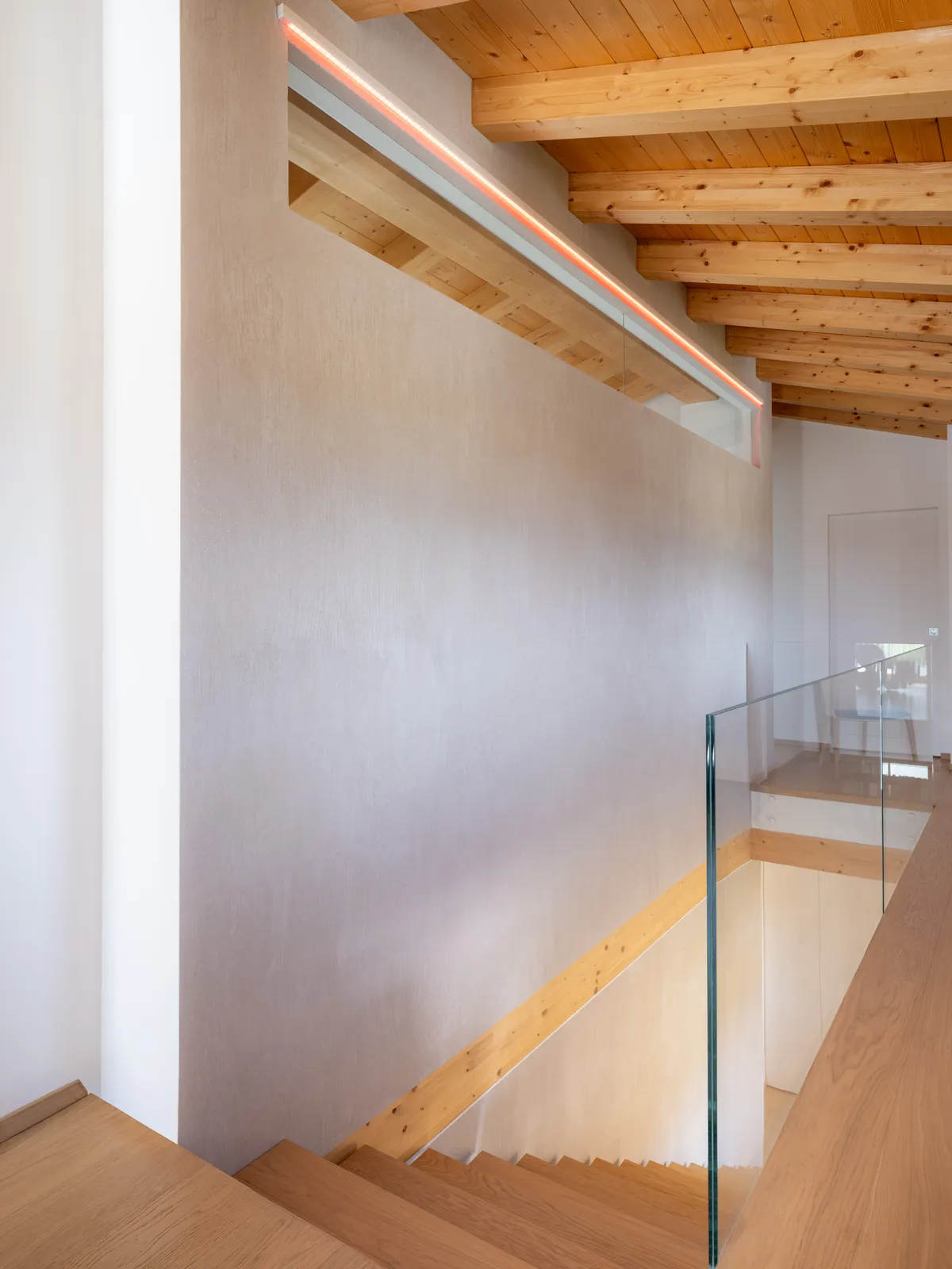 Scala con travi in legno a vista e parapetto in vetro