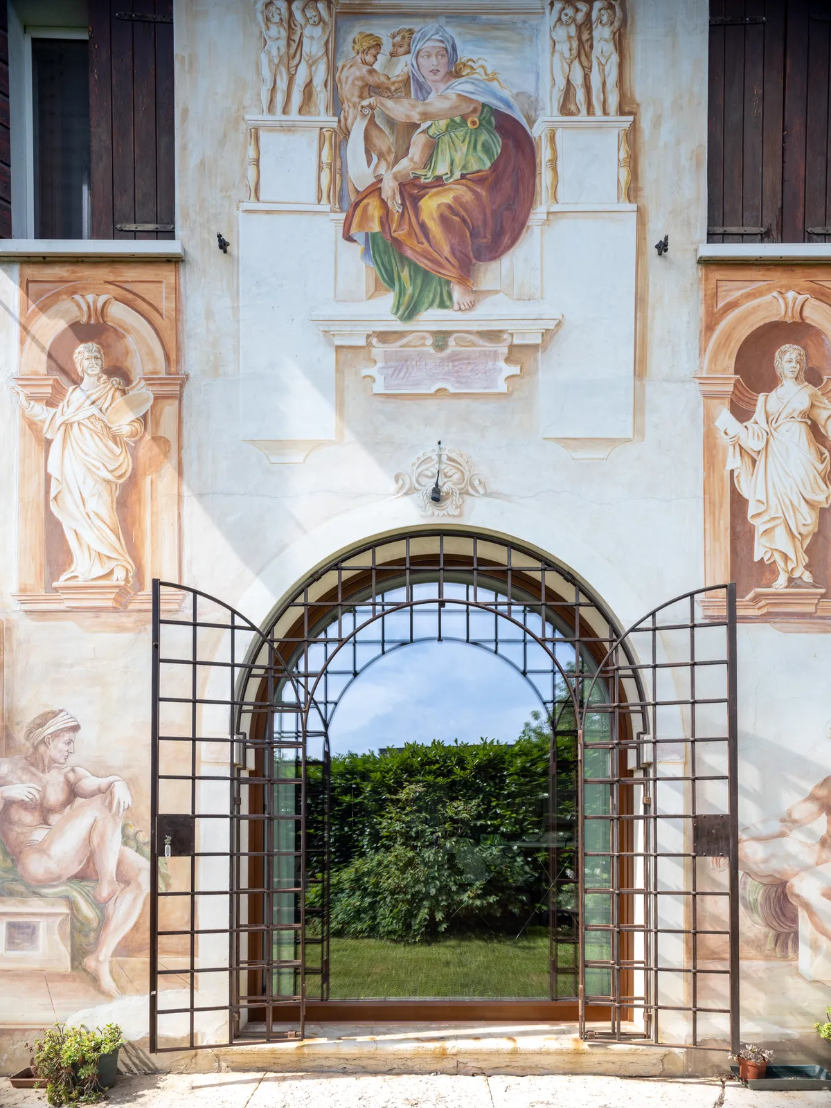 Finestra ad arco reale sotto la facciata affrescata, con l’inferriata originale aperta