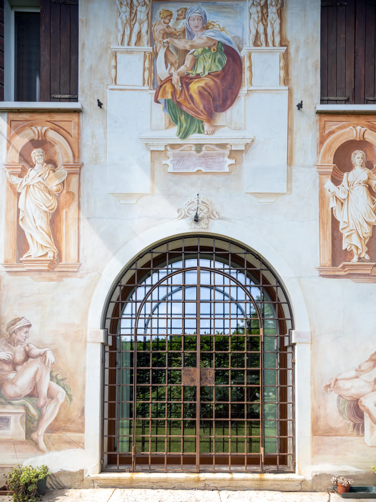 La finestra ad arco con l’inferriata chiusa e gli affreschi della facciata